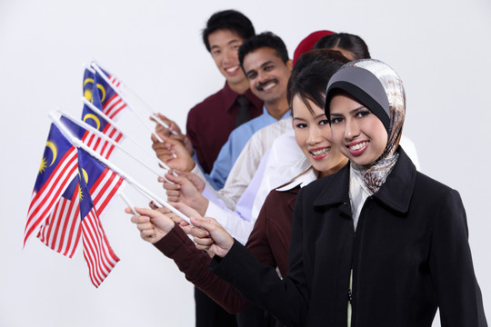 一群多种族男女手持马来西亚国旗站成一排