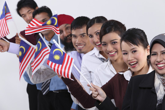持马来西亚国旗的多种族男女站成一排