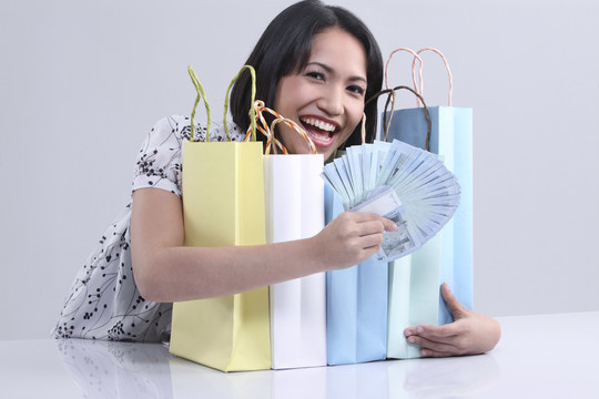 一个快乐的女人展示现金和购物袋