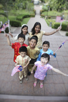穿着传统服装的孩子们举着马来西亚国旗抬头看