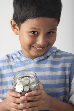 拿着装满硬币的罐子的小男孩