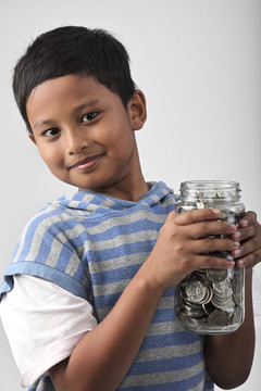 小男孩手里拿着装满硬币的罐子