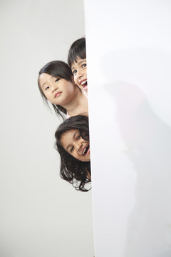 三个小女孩躲在木板后面
