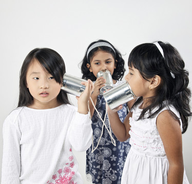 三个女孩在玩锡罐手机，互相交谈
