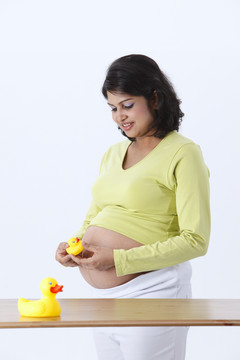 怀有身孕的妇女抱着一只黄色塑料玩具鸭。