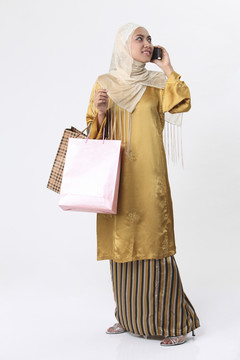 一名马来妇女拿着购物袋打电话。