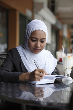 一个女人在咖啡馆的笔记本上写字。