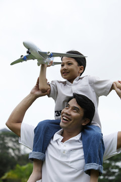 儿子抱着飞机坐在父亲肩上