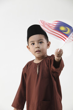 马来男孩举着马来西亚国旗看着镜头