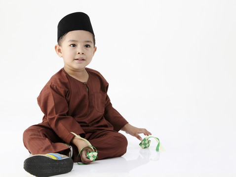 马来男孩在白色背景上玩装饰的凯图帕特