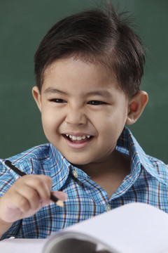 坐在教室里拿着铅笔的马来男孩