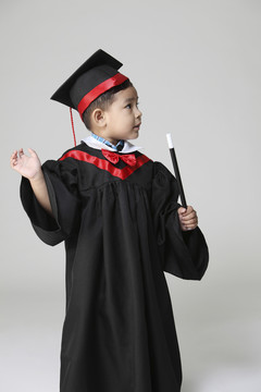 穿着毕业礼服拿着魔杖的男孩的股票图像