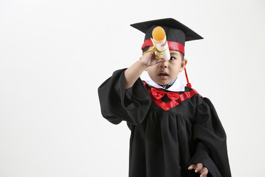穿着毕业礼服拿着毕业证书的男孩的股票图像