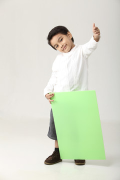 一个男孩拿着一块绿纸板，拇指朝上