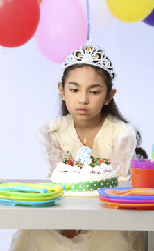 悲伤的女孩在生日蛋糕前