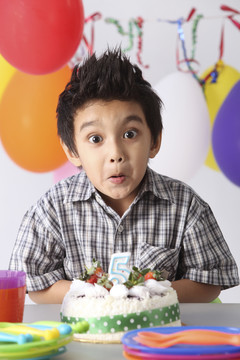 男孩在生日蛋糕前带着惊喜的表情