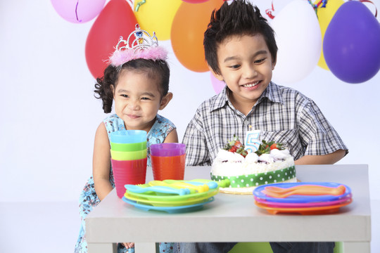 男孩和妹妹在生日蛋糕前