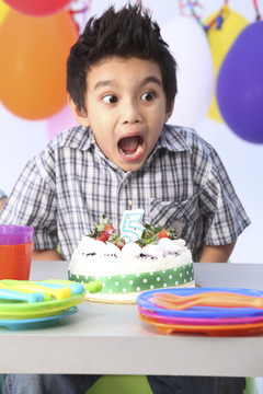 男孩在生日蛋糕前带着惊喜的表情