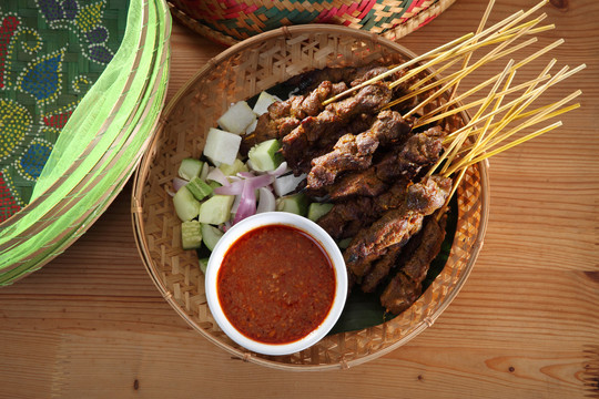 马来西亚菜沙爹在竹篮上的俯视图，上面有黄瓜和烤羊肉