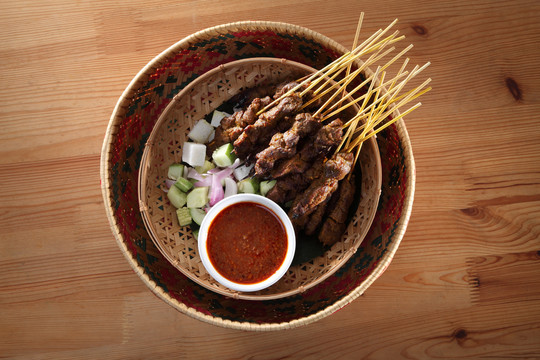 马来西亚菜沙爹在竹篮上的俯视图，上面有黄瓜和烤羊肉
