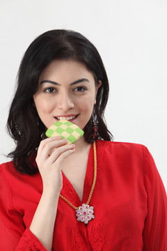 穿着红色凯巴亚的马来女人手里拿着格子饼干