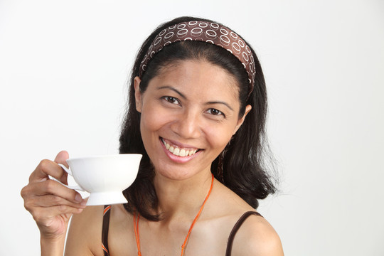 马来妇女拿着一个茶杯在笔记本电脑前