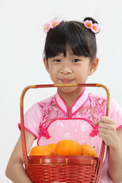 可爱的中国女孩拿着一篮橘子