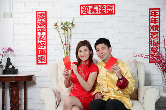 一对中国夫妇坐在沙发上用中国的新年装饰致意