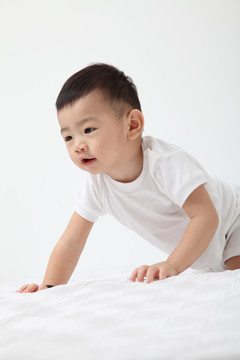 在白色背景上爬行的中国男婴
