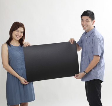幸福的中国夫妇拿着白色背景的黑卡片