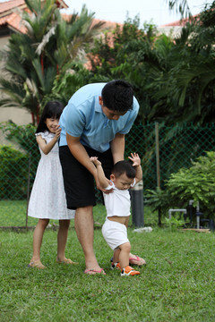 一家人在花园里引导婴儿走路