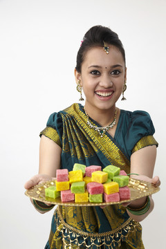 兴高采烈的印度女士手里拿着一盘糖果