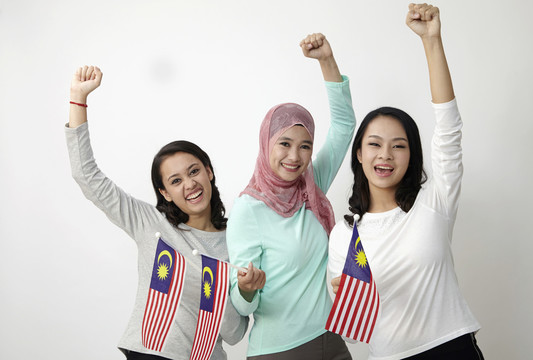 三名马来西亚多种族人士举着国旗举起手臂