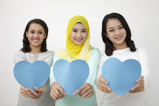 三个多种族马来西亚人拿着心形纸板看着相机