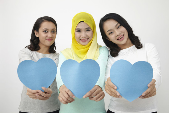 三个多种族马来西亚人拿着心形纸板看着相机