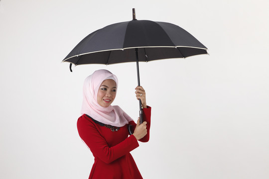 图为手持雨伞的马来妇女的概念照片