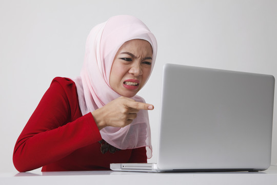 坐在笔记本电脑前的马来妇女生气地问