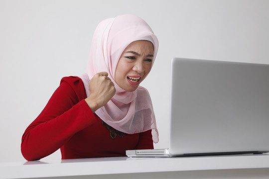 坐在笔记本电脑前的马来妇女生气地问