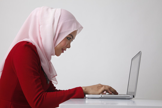 马来妇女使用笔记本电脑的侧视图