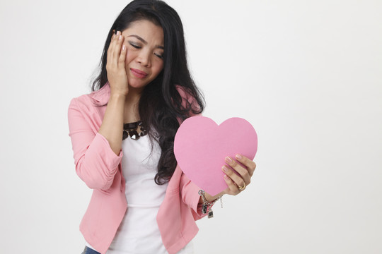 一个马来女人手里拿着一张甜美的粉红色心形纸