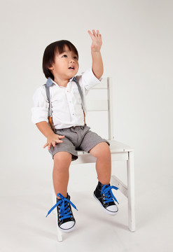 中国男孩坐在大凳子上举手