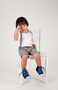 中国男孩坐在大凳子上举手