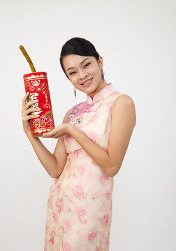 微笑的中国女人穿着传统旗袍手持大爆竹
