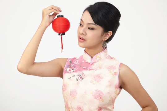 微笑的中国女子手持红灯笼，身着传统旗袍