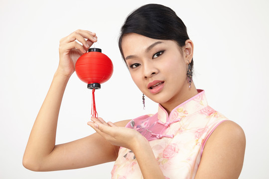 微笑的中国女子手持红灯笼，身着传统旗袍
