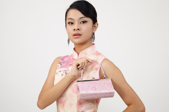 微笑的中国女人在新年穿着传统旗袍，手里拿着一个可爱的手袋