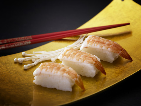 用筷子把虾寿司放在盘子里