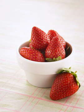 一碗草莓，前面有一个草莓