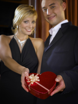 男人和女人穿着晚装手持心形盒子