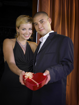 男人和女人穿着晚装手持心形盒子